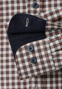 Braun- und cremefarbener kariertes Hemd mit schwarzen Knöpfen; verfügt über einen Denim-Manschette mit Nähdetails und einem kontrastierenden Kragen.