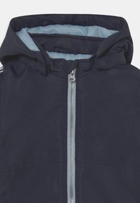 Giacca con cappuccio blu navy con fodera azzurro chiaro, zip a tutta lunghezza e senza motivi o dettagli visibili. Tessuto liscio e materiale leggero.