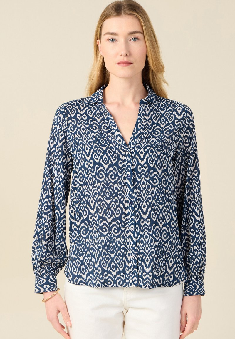 Camicia a maniche lunghe blu navy con un motivo bianco a spirale, chiusura con bottoni e colletto. Realizzata in tessuto morbido con una vestibilità comoda.