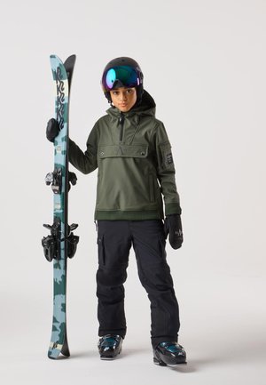 Ski equipment with an green hoodie, black ski pants, black gloves, and a helmet with a mirrored visor, holding patterned skis.