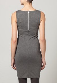 Grå ärmlös klänning med en figurnära design, texturerad tyg och en dragkedja baktill. Nederkanten slutar strax ovanför knäna.