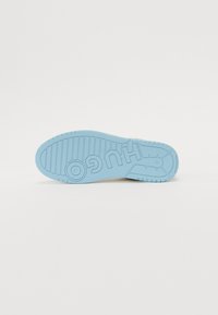 Sole di sneaker azzurro chiaro in gomma, con superficie di presa testurizzata, motivi orizzontali e verticali, e dettaglio logo in rilievo.