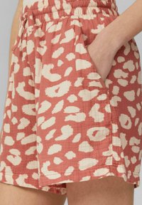 Leichte, korallenfarbene Shorts mit einem cremefarbenen abstrakten Muster. Elastischer Bund, verstellbarer Bindegürtel, Seitentaschen und eine weiche, strukturierte Oberfläche.