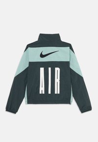 Nike jakna ima visoki ovratnik, dvobojni dizajn u tamnozelenoj i svijetloj tirkiznoj boji, s istaknutim bijelim printom "AIR" i crnim swoosh logom.