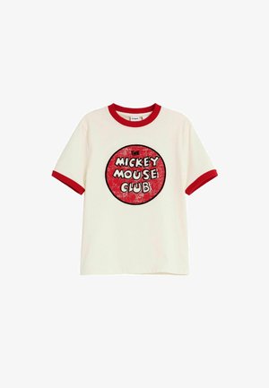 Biała koszulka z krótkim rękawem z czerwonym kołnierzykiem i krawędziami rękawów, z przetartym czerwonym kołem z napisem "The Mickey Mouse Club" pośrodku.