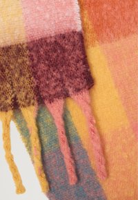 Écharpe en laine avec un motif à carreaux dans des teintes de rose, jaune, bordeaux et orange ; comprend des franges avec une finition texturée.