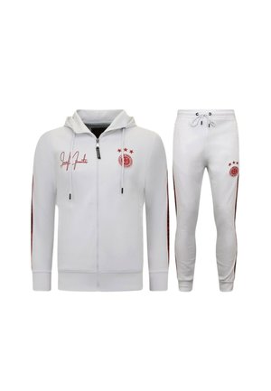 Witte zip-up hoodie en bijpassende joggerbroek met rode strepen op mouwen en benen, rode ster en cirkelvormige logodetails.