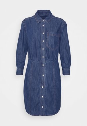 Tummansininen denim-nappimekko, jossa on muotoiltu vyötärö, lyhyet hihat ja polven ylle ulottuva helma, yhdistettynä metallinhohtoisiin kultaisiin korkokenkiin.