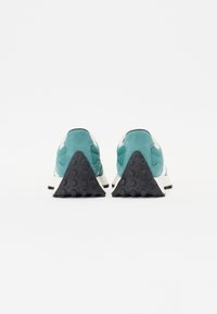 Sneaker turchesi e bianchi con una tomaia in suede testurizzato, dotate di una suola in gomma nera triangolare e di un collo imbottito per il comfort.