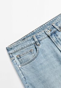 Light blue denim jeans with a faded wash, featuring a front pocket, belt loops, and silver button closure at the waistband.