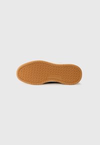 Rubber shoe sole with a textured, circular pattern in tan color, featuring a raised logo and a smooth edge for grip and durability.