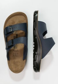 Navy blue sandals with two adjustable straps, a contoured cork footbed, and a textured black rubber outsole for grip and comfort.