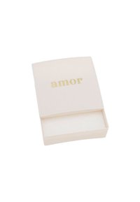 Caja rectangular de color crema suave con una inscripción dorada de "amor" en la tapa; textura lisa, se abre a un interior blanco.