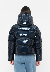 Marineblauwe glanzende pufferjack met capuchon, met horizontale stiksels en een korte snit. Het materiaal heeft een gladde, glanzende textuur.