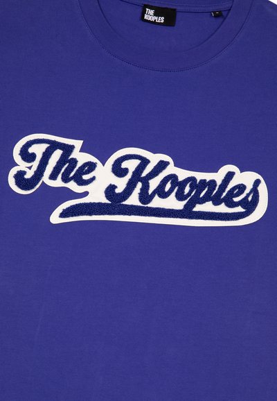 Lila Baumwoll-T-Shirt mit erhabener Schrift in Weiß und Marineblau, die "The Kooples" liest. Klassischer Rundhalsausschnitt mit kurzen Ärmeln.