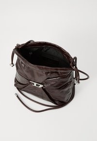 Brown leather bucket bag with gathered design, silver hardware, and a drawstring closure. Features an interior pocket and smooth texture.