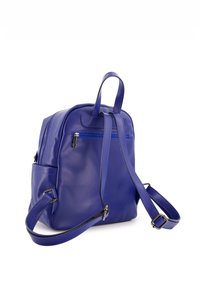 Sac à dos en cuir violet avec des bretelles réglables, poche avant zippée et texture lisse. Comprend des accents en métal argenté.