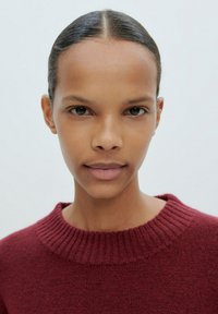 Bordeauxfarbener Pullover mit geripptem Ausschnitt, aus einem weichen strukturierten Stoff gefertigt, mit lockerer Passform und minimalistischem Design.