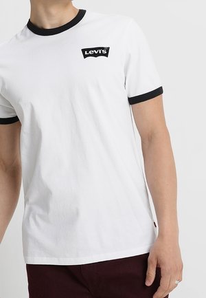 Biała koszulka z krótkim rękawem z czarną lamówką na kołnierzyku i rękawach, z małym czarnym logo Levi's na lewej piersi.