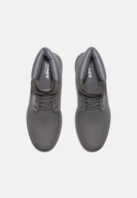 Chaussures grises imperméables avec une finition lisse, un design à lacets, un col rembourré et une semelle en caoutchouc texturée pour une meilleure adhérence.