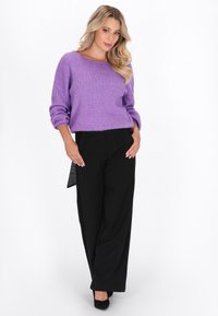 Paarse trui met lange mouwen van zacht materiaal, gecombineerd met een hoge taille zwarte wijde broek. De trui heeft een bootneck ontwerp.