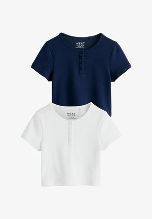 Două topuri tricotate scurte cu mâneci scurte, cu gât rotund și cu patru nasturi pe partea frontală, una bleumarin și una albă, așezate pe o suprafață plană.