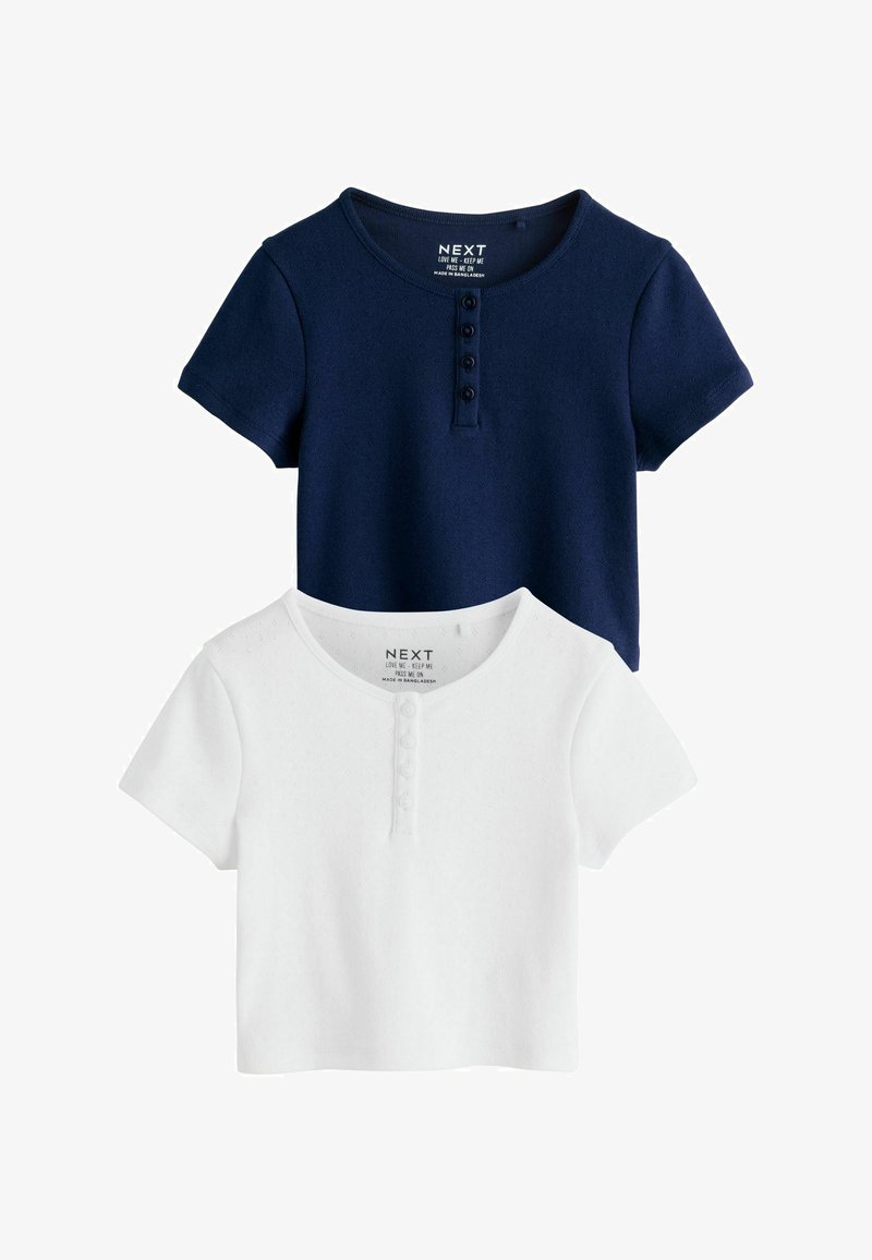 Deux hauts courts à manches courtes en maille avec encolure ronde et patte de boutonnage à quatre boutons, un bleu marine et un blanc, posés à plat.