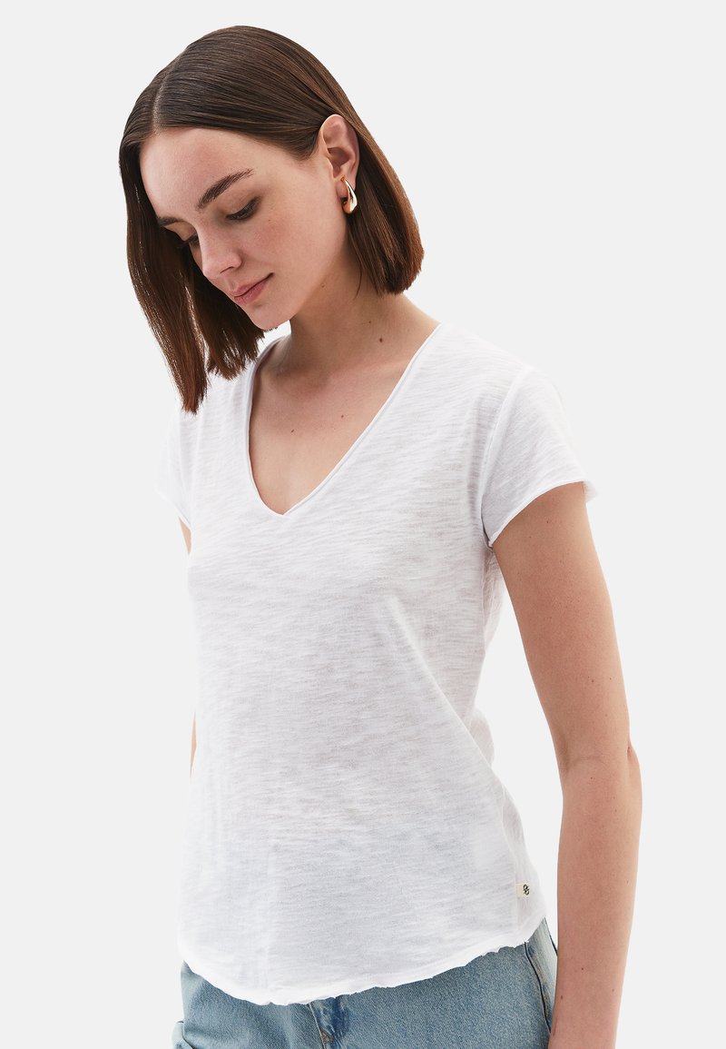 Witte V-hals t-shirt van lichtgewicht, gestructureerde stof. Korte mouwen, ruime pasvorm en een subtiele, gebogen zoom. Klein logo detail aan de zijkant.