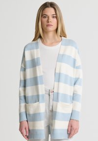 Juostuotas švarkas šviesiai mėlynos ir grietinėlės spalvos, su laisvu fasonu, ilgomis rankovėmis, patemptais rankogaliais ir dviem priekinių kišenių. Minkšta mezgimo tekstūra.