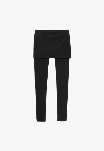 Legging noir avec une jupe courte par-dessus, sur fond blanc.