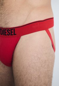 Piros pamut tanga fekete "DIESEL" logóval az elasztikus derékpánton, minimalista dizájnnal és sima felülettel.