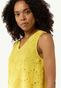 Żółty top bez rękawów z misternym haftem, dekoltem w kształcie V oraz teksturowanym materiałem o miękkim, lekkim wyglądzie.