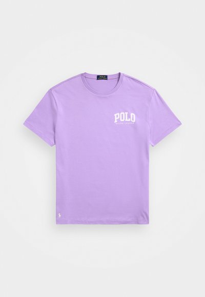 Világoslila pamut póló, amelyen fehér "POLO" logó található a bal mellrészen és egy kis hímzett logó az alsó szegélyen. Kerek nyakú kialakítás.