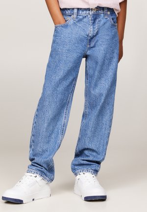 Jeans in denim blu chiaro con vestibilità rilassata, caratterizzati da una superficie testurizzata, cinque tasche e cuciture visibili. Indossati con sneakers bianche.