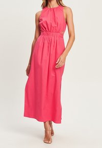 Robe maxi rose à dos nu avec une taille froncée, des découpes latérales et une texture lisse. Présente une silhouette fluide et un ourlet longueur cheville.