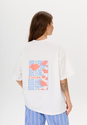Witte oversized t-shirt met korte mouwen, voorzien van een kleurrijke grafische print in roze en blauw op de achterkant, met verschillende zinnen.