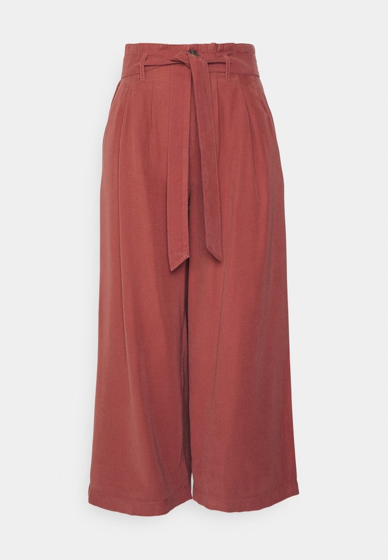 Rust-colored wide-leg pants with a belted waist, featuring a smooth texture and pleats along the front for added detailing.