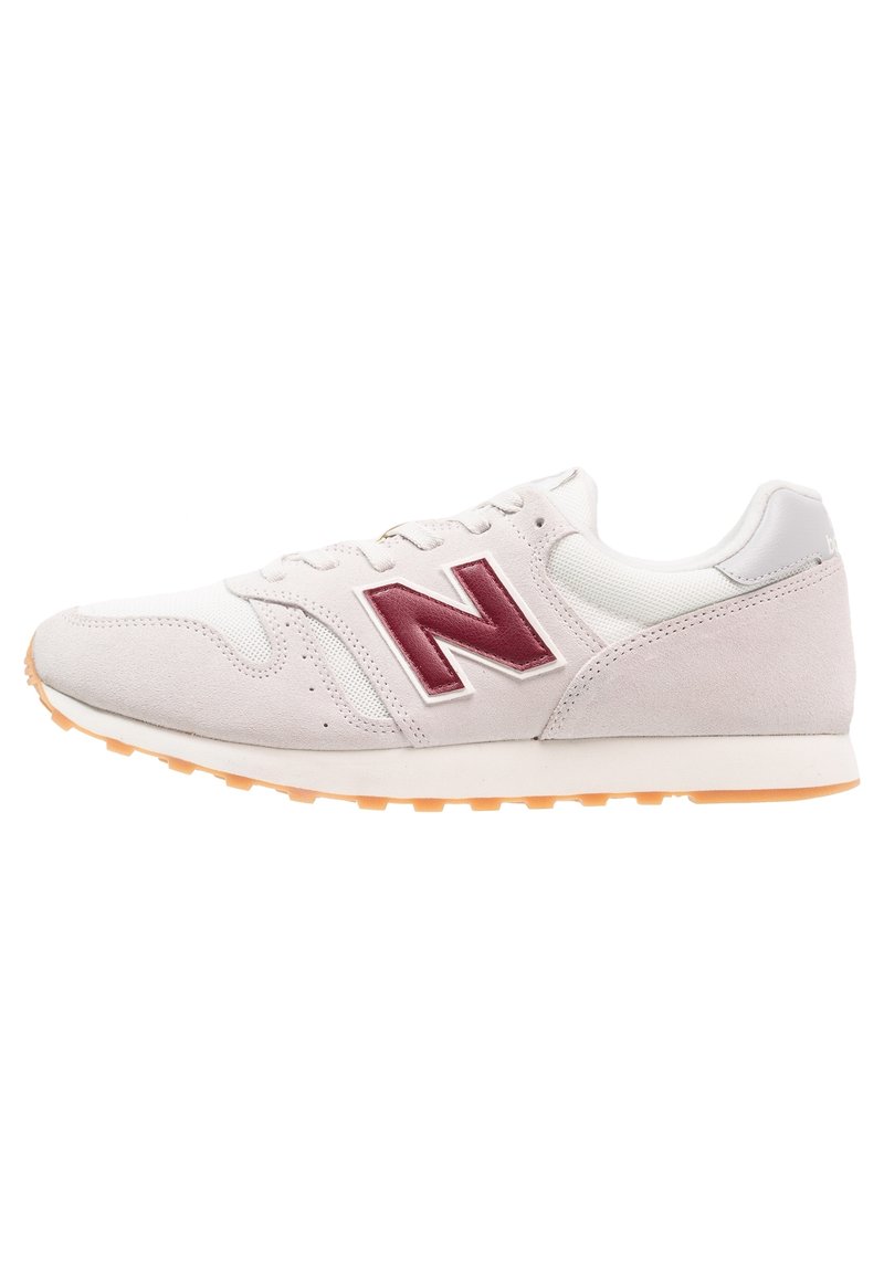 Baskets gris clair avec une tige en daim et en mesh, arborant un logo bordeaux, des accents blancs et une semelle en caoutchouc orange. Design rétro classique.
