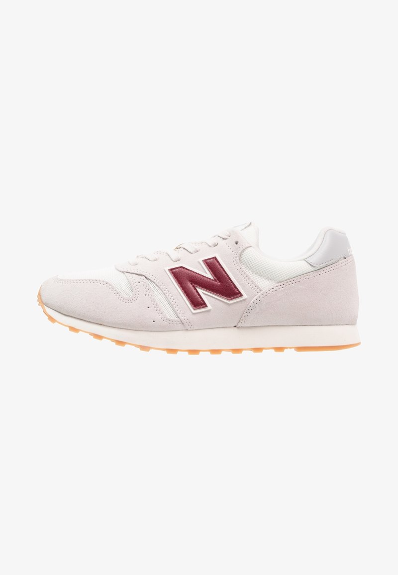 Baskets gris clair avec une tige en daim et en mesh, arborant un logo bordeaux, des accents blancs et une semelle en caoutchouc orange. Design rétro classique.