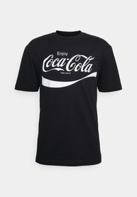 Černé bavlněné tričko s velkým bílým logem Coca-Cola, zakřiveným bílým pruhem pod ním, krátkými rukávy a kulatým výstřihem.