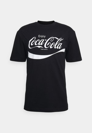 T-shirt en coton noir présentant un grand logo Coca-Cola blanc, avec une bande blanche courbée en dessous, des manches courtes et un col rond.