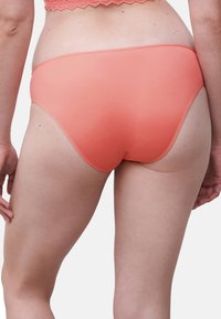 Korallenfarbene Unterwäsche mit glattem Stoff, einem niedrigen Schnitt und dezenten Nähten. Der Bund hat eine schmale Kante.