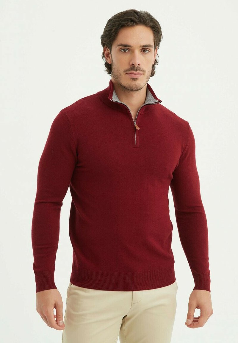 Pull en maille bordeaux à col zippé, fabriqué dans un tissu doux, avec un col intérieur gris contrastant, une silhouette ajustée et des manches longues.