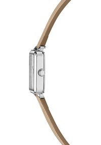 Montre pour femme avec un boîtier rectangulaire en argent, un bracelet en cuir marron clair et un détail de couronne sur le côté ; design minimaliste avec des surfaces lisses.