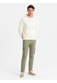 Bavlněná mikina v off-white barvě s přední kapsou a kapucí na šňůrku. Koordinované olivové cargo kalhoty mají boční kapsy a zipové detaily.
