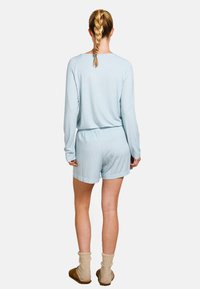 Helles blaues Schlafanzug-Set mit einem langärmligen Oberteil und Shorts mit einem subtilen geometrischen Muster. Weicher Stoff, elastischer Bund und lockere Passform.