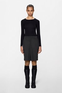 Μαύρο μακρυμάνικο τοπ, σκούρα γκρι cargo σορτς με πλαϊνές τσέπες και μαύρες λαστιχένιες μπότες μέχρι το γόνατο. Λείο ύφασμα, εφαρμοστή γραμμή.