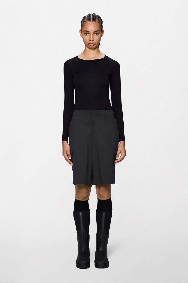 Μαύρο μακρυμάνικο τοπ, σκούρα γκρι cargo σορτς με πλαϊνές τσέπες και μαύρες λαστιχένιες μπότες μέχρι το γόνατο. Λείο ύφασμα, εφαρμοστή γραμμή.