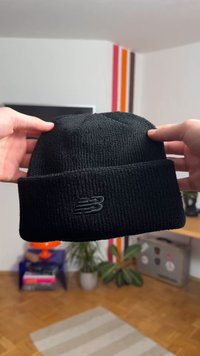 Black knit beanie with a folded cuff, featuring a subtle black logo. The texture appears ribbed, suitable for cold weather wear.