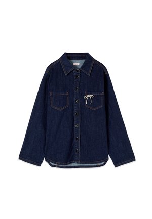 Ciemnoniebieska koszula jeansowa z długim rękawem na guziki, z dwoma przednimi kieszeniami, z których jedna ma małą białą kokardkę ze sznurka.